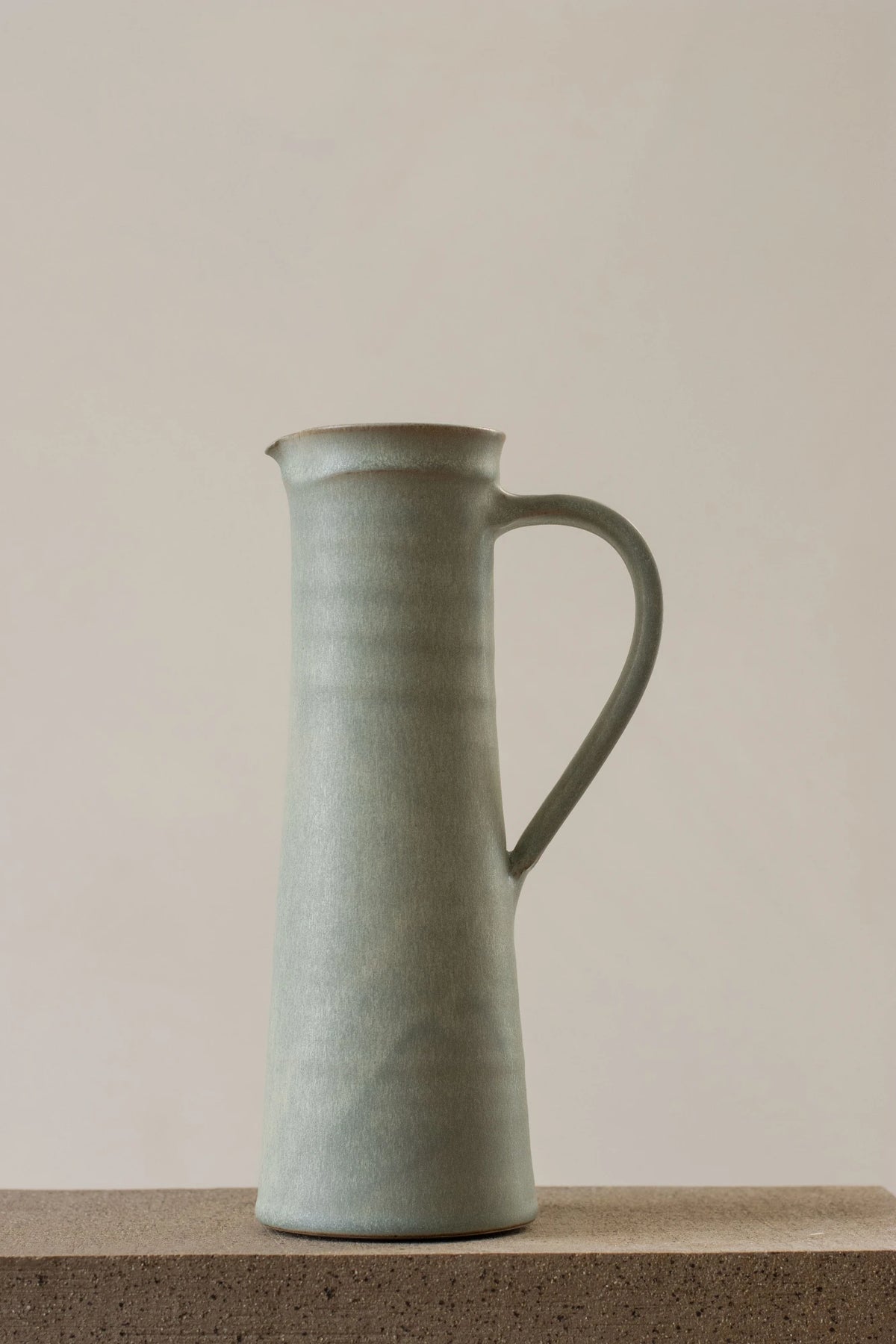 A Borja Moronta jug in mist blue glaze sitting on a stone counter
