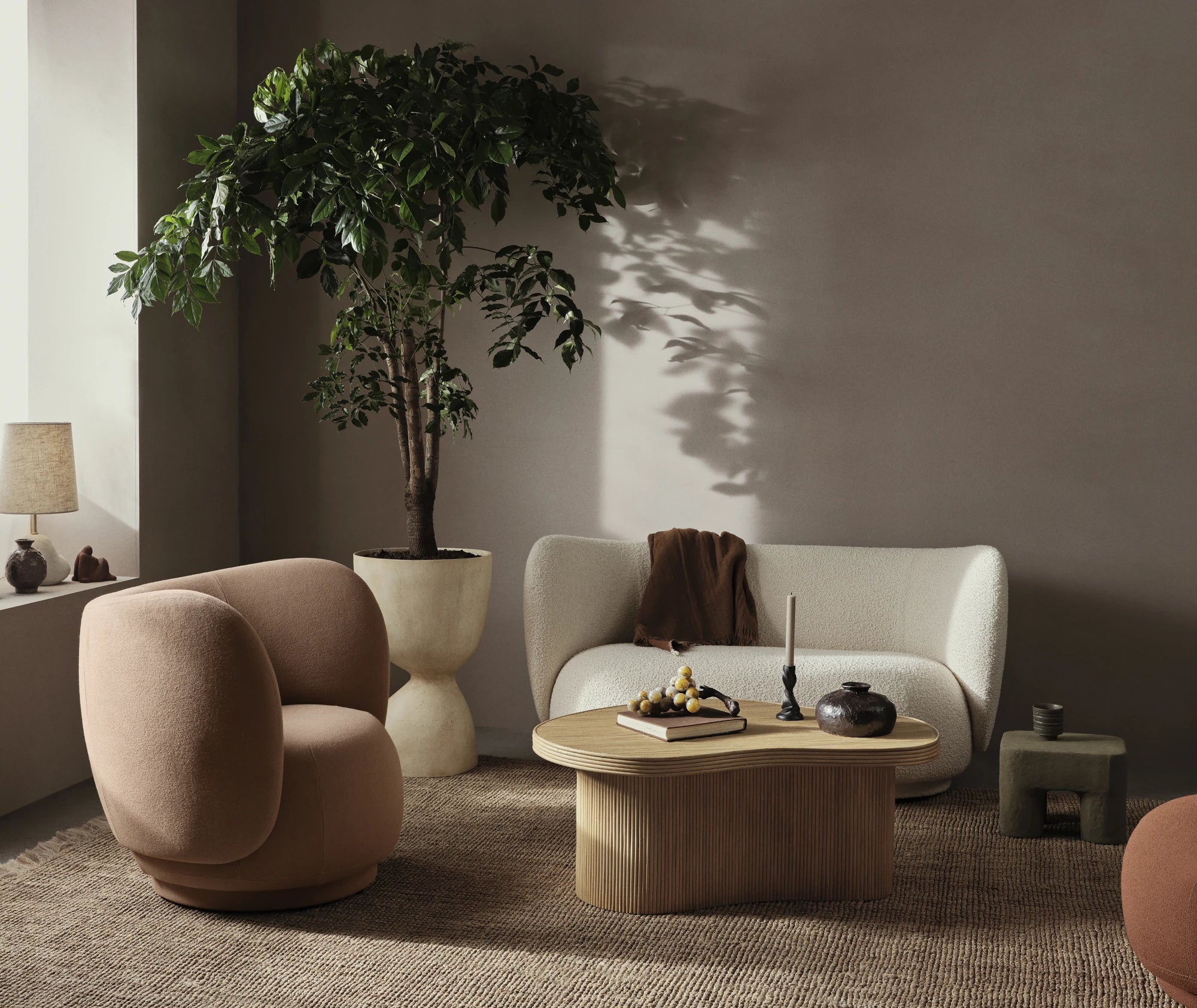 Ferm Living Rico 2-Seater Sofa and Rico Loung Chair in an Earth toned living room with a large plant behind them