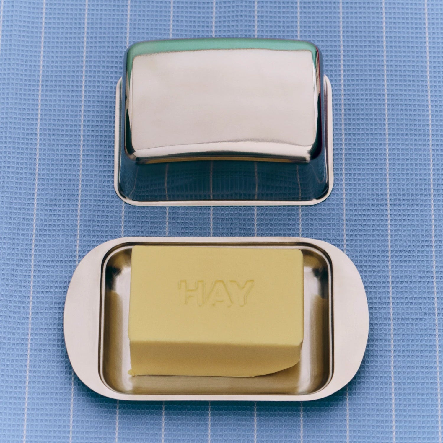Butter dish with a bar of butter labelled 'HAY' on a blue grid background
