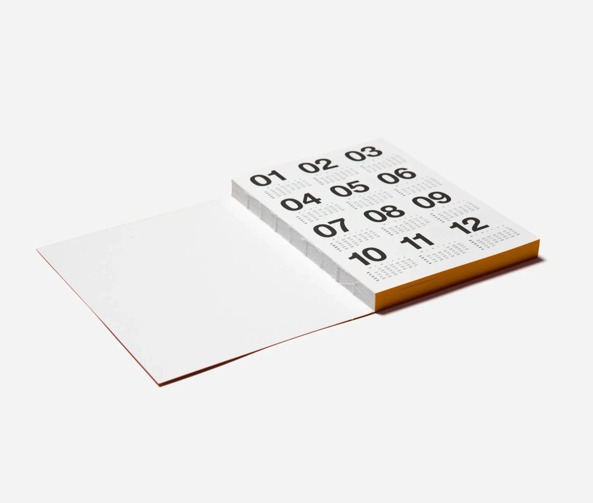 A Marjolein Delhaas planner with a white interior, black Arabic numerals from 01 to 12 on the top page, and an orange spine, shown on a clean light gray background.