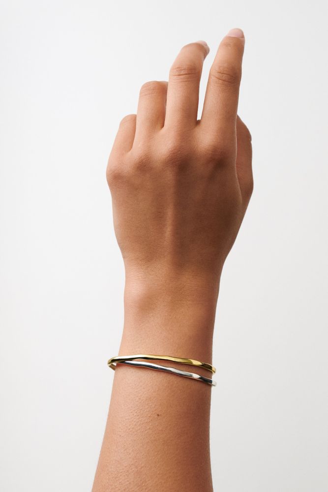 Hand wearing a gold bracelet on a white background