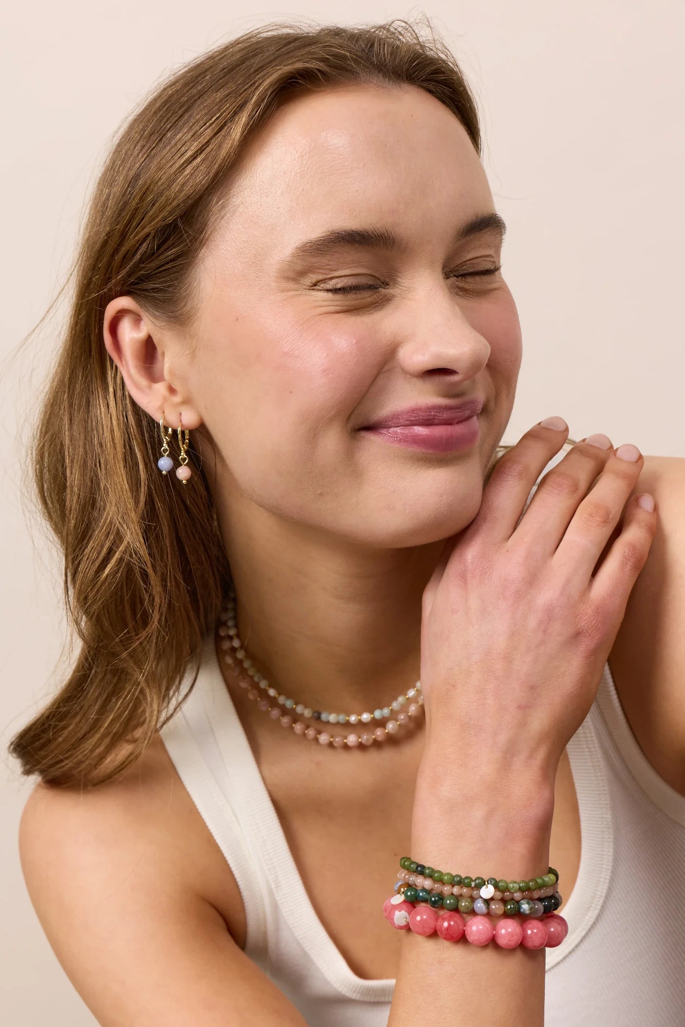 Woman wearing Soï Copenhagen Ava huggie hoop earrings in 18k gold with a Aquamarine stone