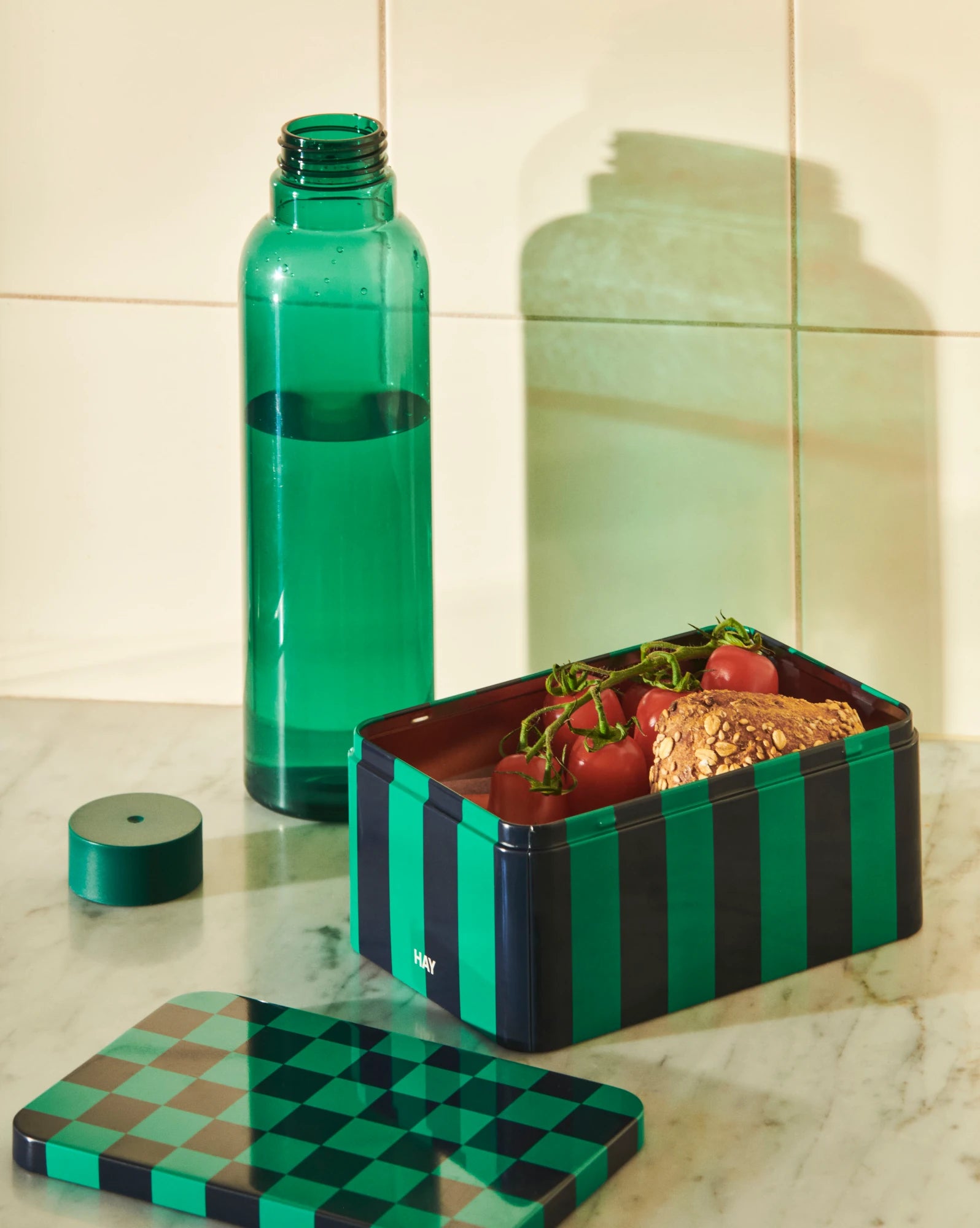 Small Tin Container in dark blue and green with a Miz dark green water bottle on a counter by HAY | Lifestory