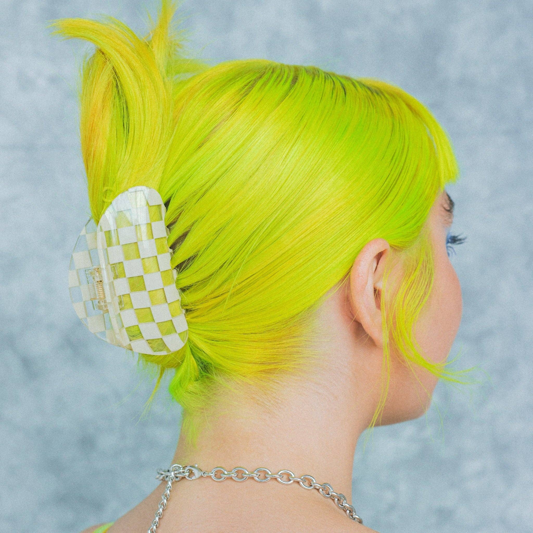 CHUNKS Checker Hair Claw in Clear being worn by a model with fluorescent yellow green hair in an up do