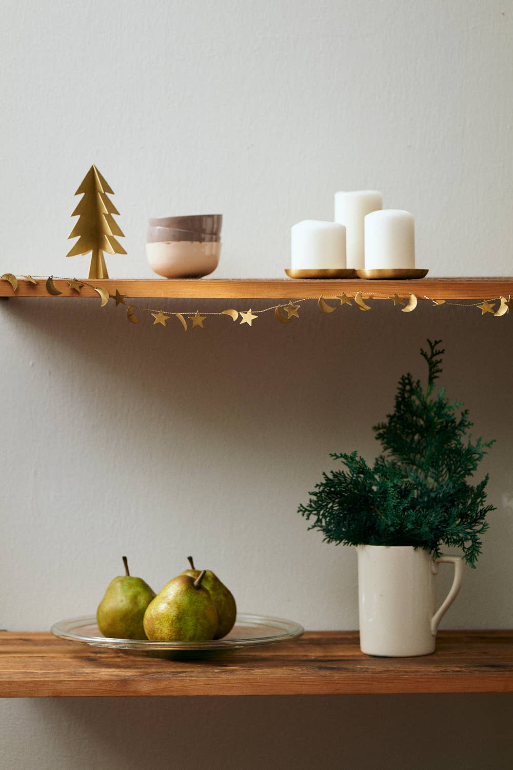 Wooden shelves with decorative items including pears, a mug with a plant, and candles.