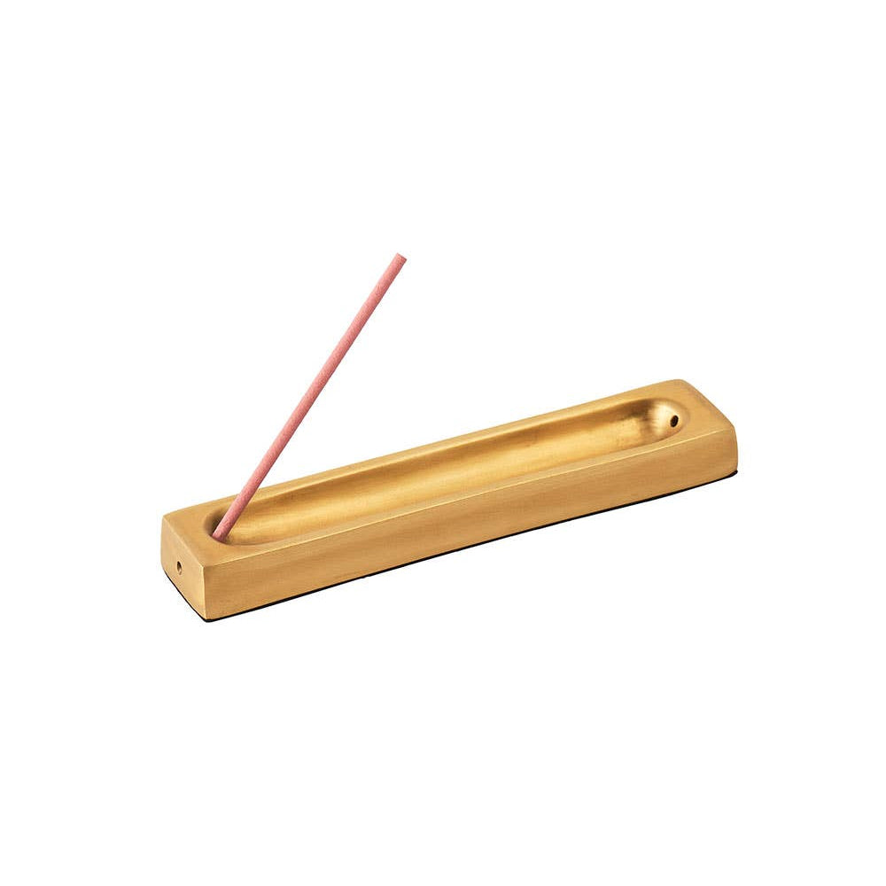 Brass incense holder with a single pink incense stick on a white background