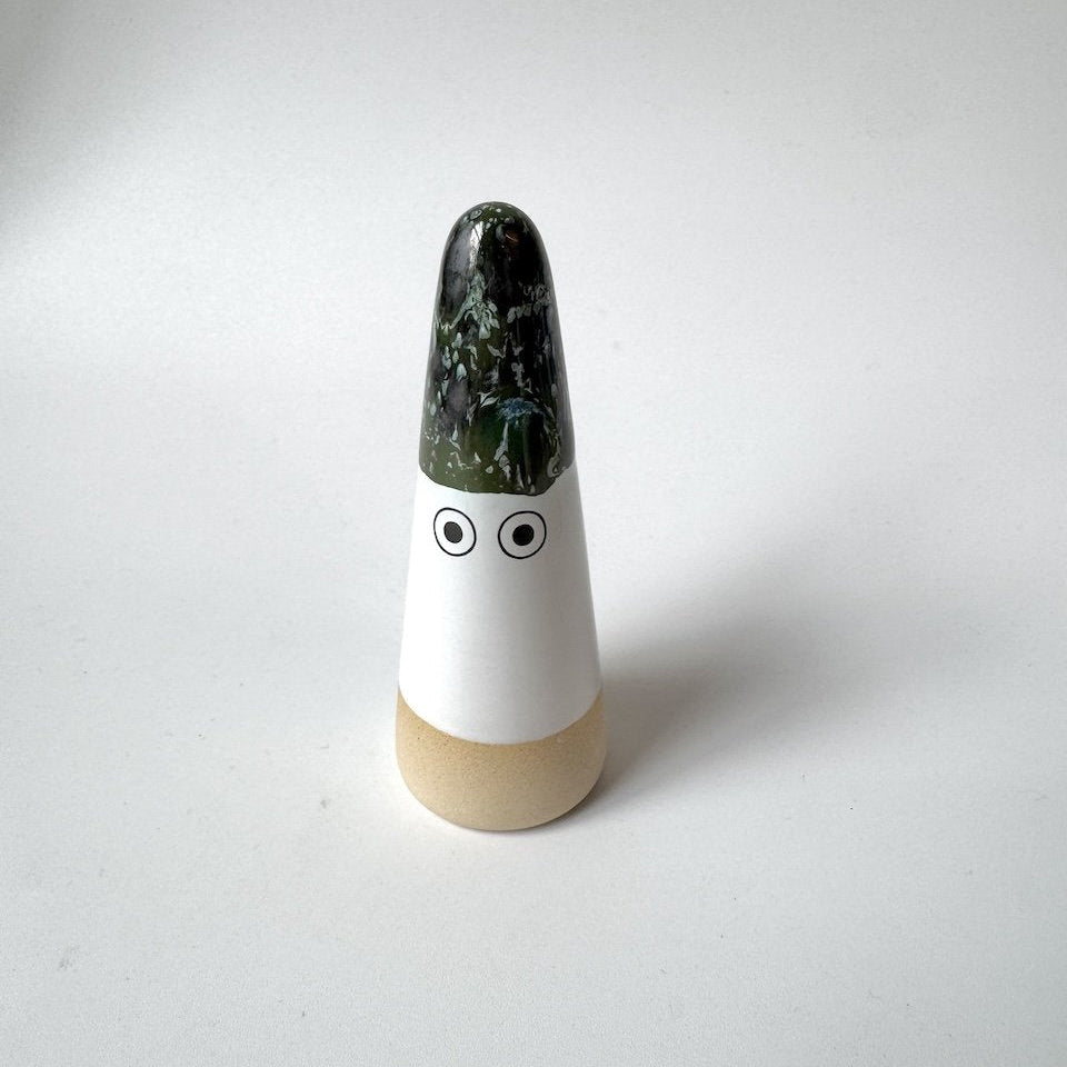 Sed Studio Arhoj ghost with a glossy dark green glazed top, a white middle section with two simple black eyes, and a light beige base, set against a plain light grey background.
