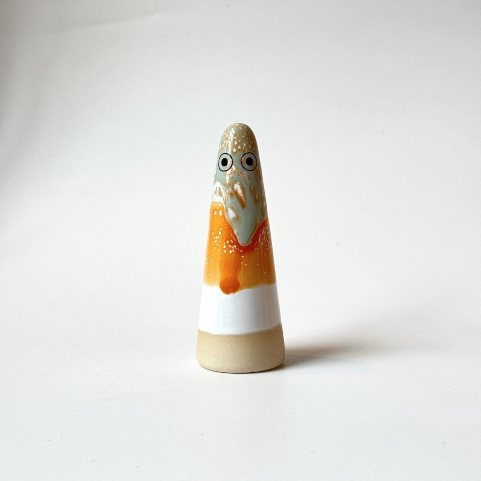 Bee Stuido Arhoj ghost, featuring a hand-painted face and body in orange, white, and beige glazes, set against a plain white studio background.