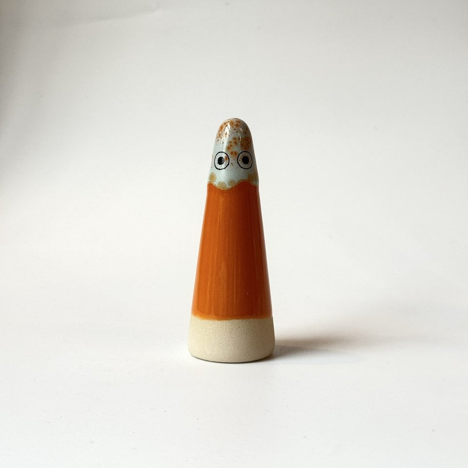 Freyja Studio Arhoj ghost, featuring an orange body, a cream-colored base, and a face with large black eyes and a patterned beige top.