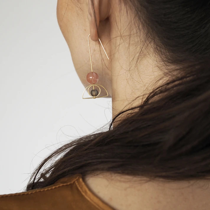 Close up view of Pink & Grey Arch & Circle Brass Earrings by brass+bold being worn by a white model with dark brown hair