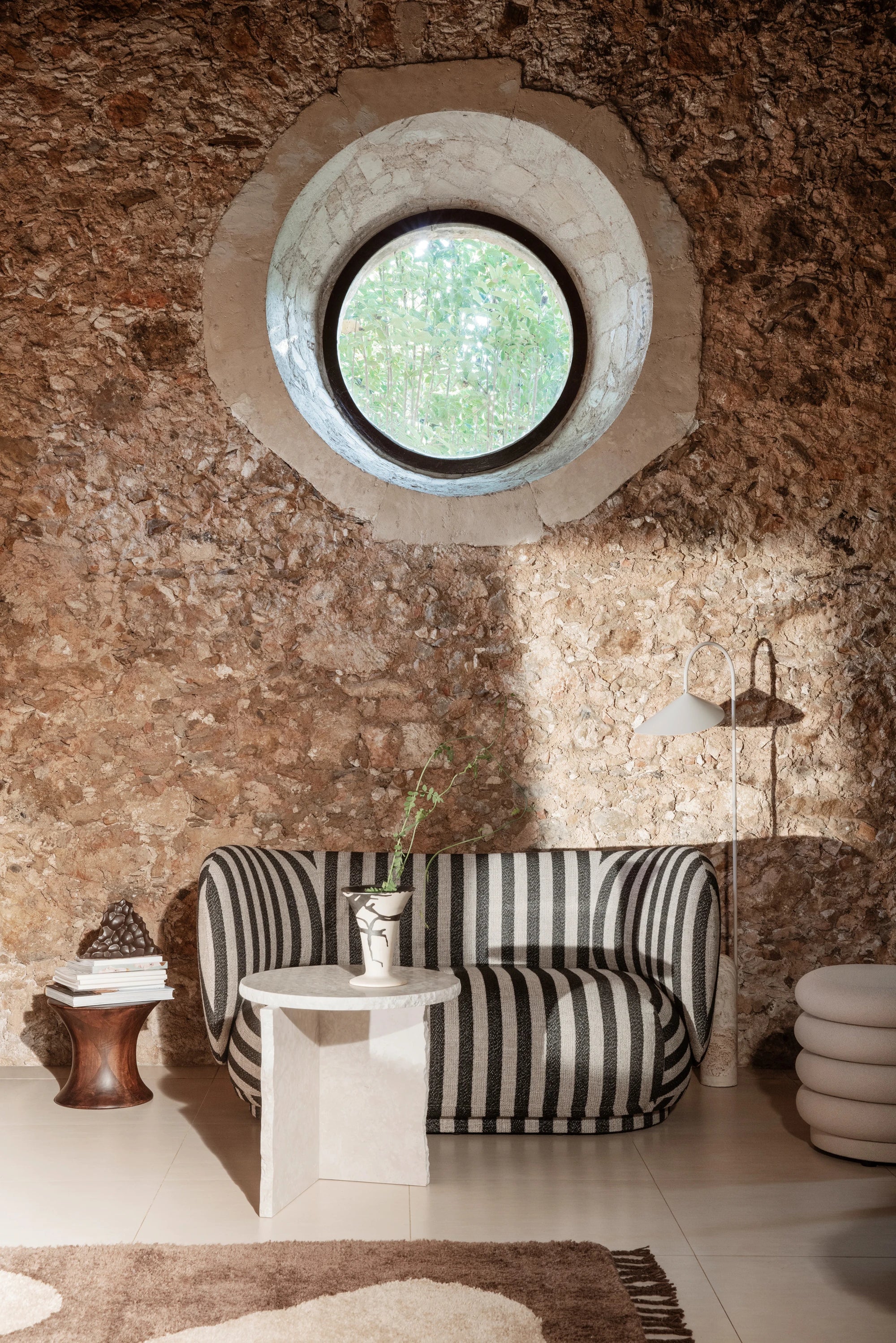 Ferm Living Rico 2-Seater Sofa in Louisiana stripe fabric in a well lit room with a stone wall back drop
