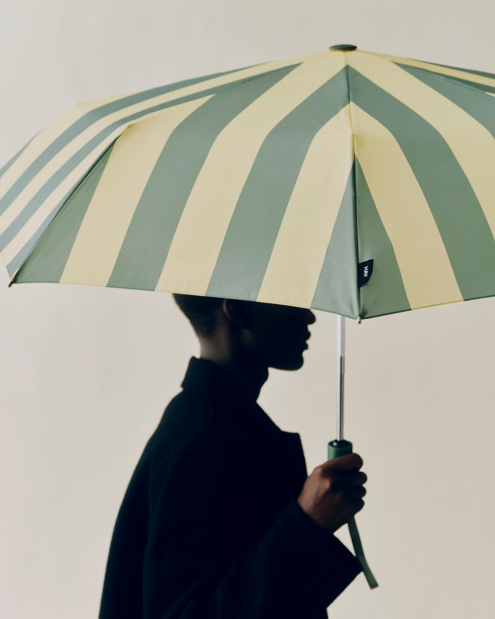 HAY soft yellow Regn umbrella held by a model