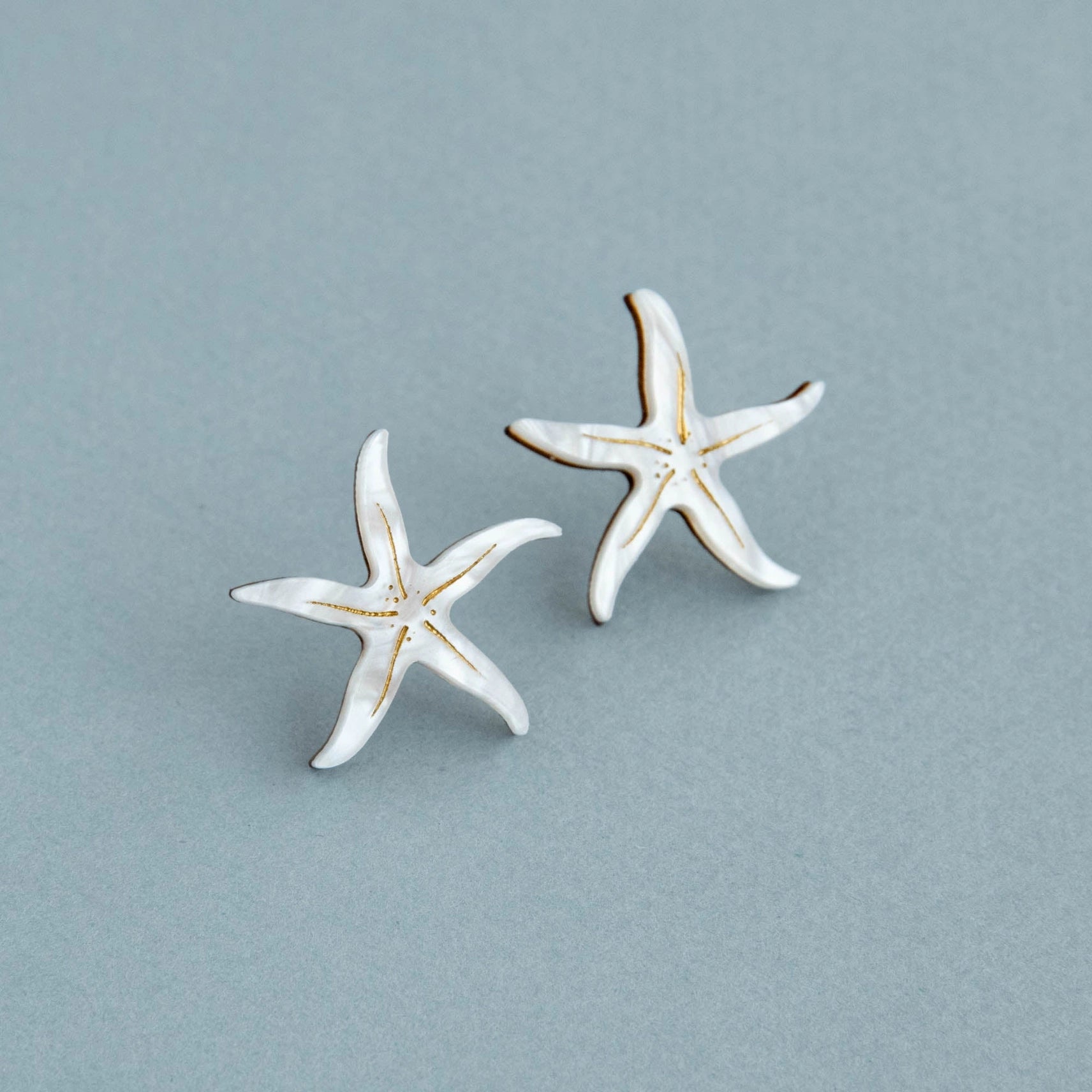 Pepper You Acrylic & Wood Starfish Stud Earrings on a blue background