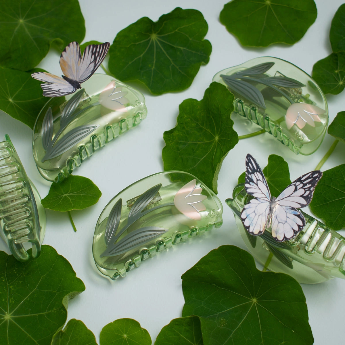 Clear hair clips with lotus flower designs on green leaves with butterflies