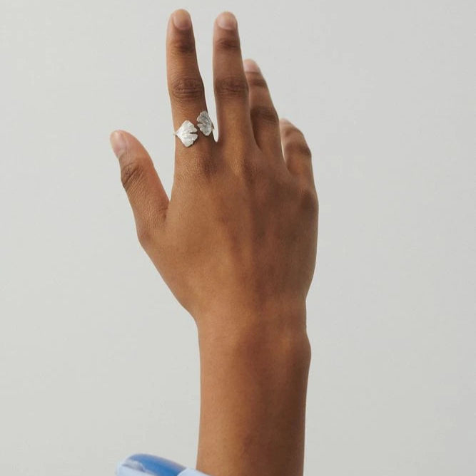 Biloba Ring in Silver by Pernille Corydon on a models hand against a cream background with a pale blue sleeve visible at the bottom of the image