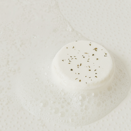 White bar of soap with specks on a white background